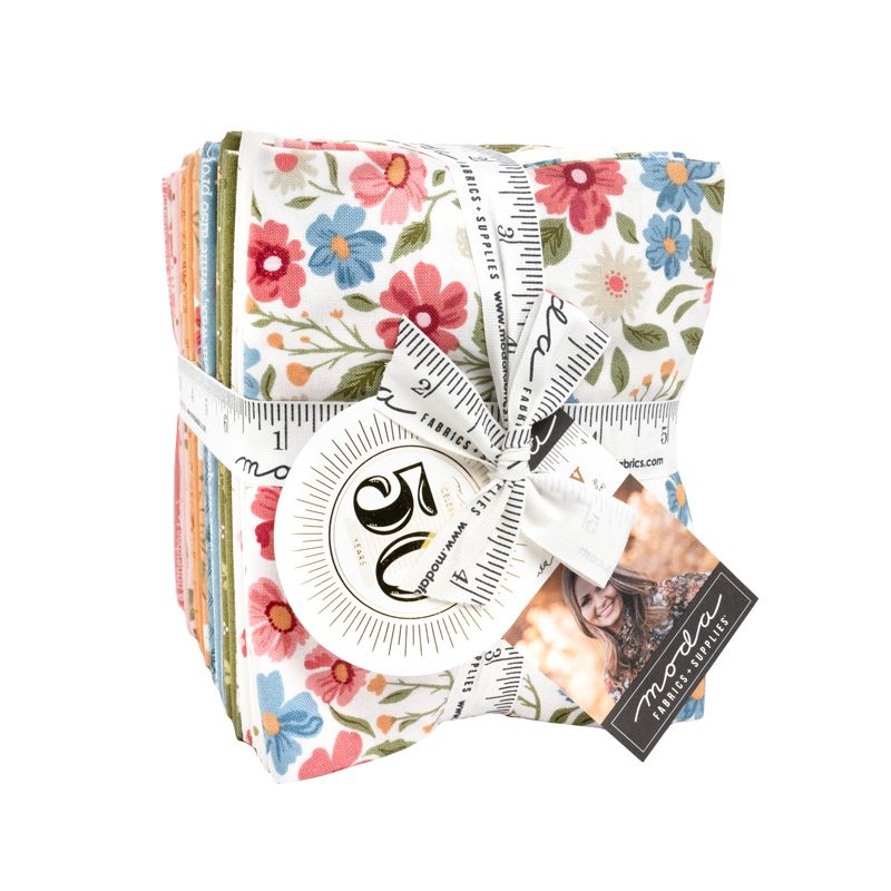 A stack of floral-patterned fabric pieces tied with a white measuring ribbon and tape measure, with a brand tag attached, on a plain white background.