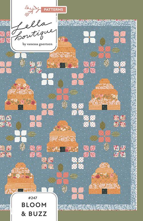 Pattern cover for Bloom & Buzz by Vanessa Goertzen of Lella Boutique, pattern number 2447, titled 'Bloom & Buzz'. The design features a slate blue background with a repeating pattern of orange-brown beehives and pink, white, and green floral blocks.