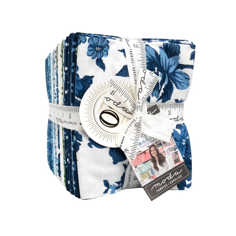 A bundle of fabric quilts wrapped in a white ribbon with a measuring tape design and a bow, featuring a blue floral pattern on a white background. A tag on the ribbon reads 'moda fabric supplies'.