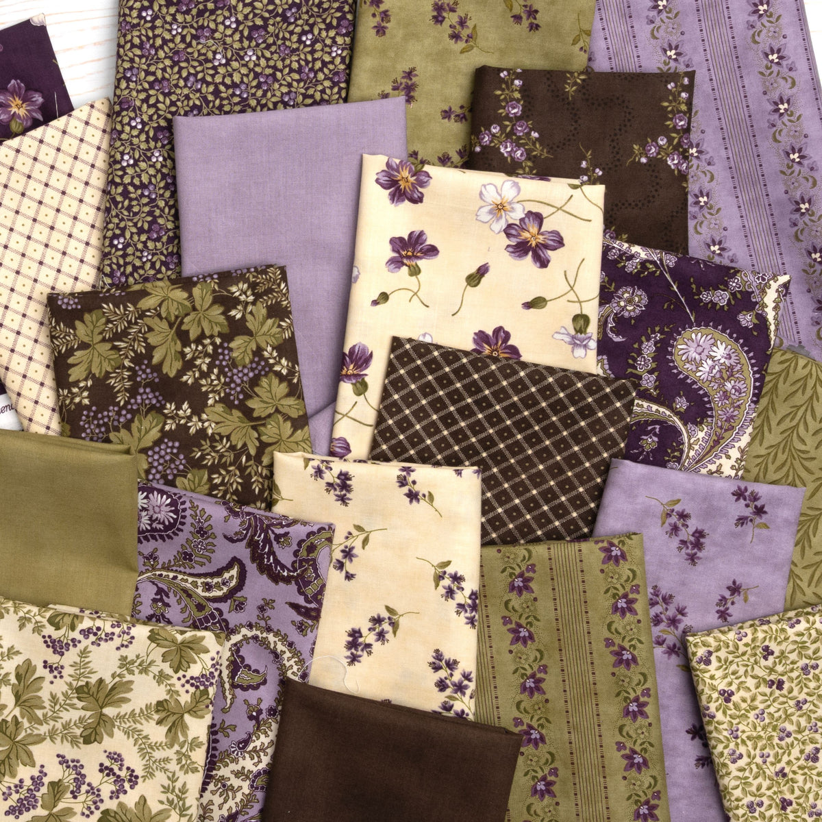 A flat-lay arrangement of multiple fabric squares in earthy tones, including purple, olive green, brown, beige, and floral patterns.