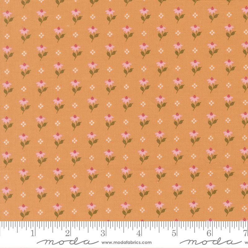 A close-up of a fabric pattern featuring small pink and white flowers with green stems on a warm peach-orange background, with a measuring ruler along the bottom edge showing the scale.