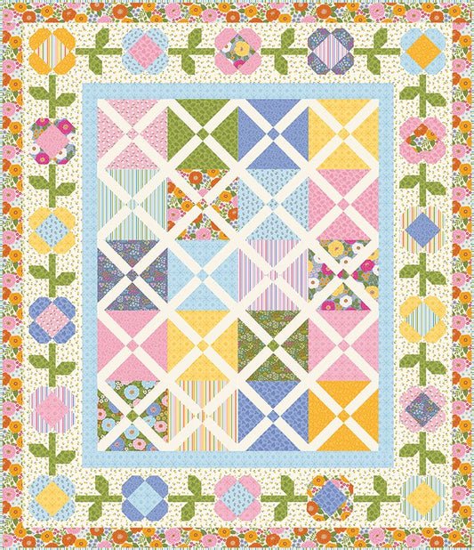 A colorful patchwork quilt with a floral border, featuring geometric blocks in pink, blue, yellow, green, and white on a cream background.