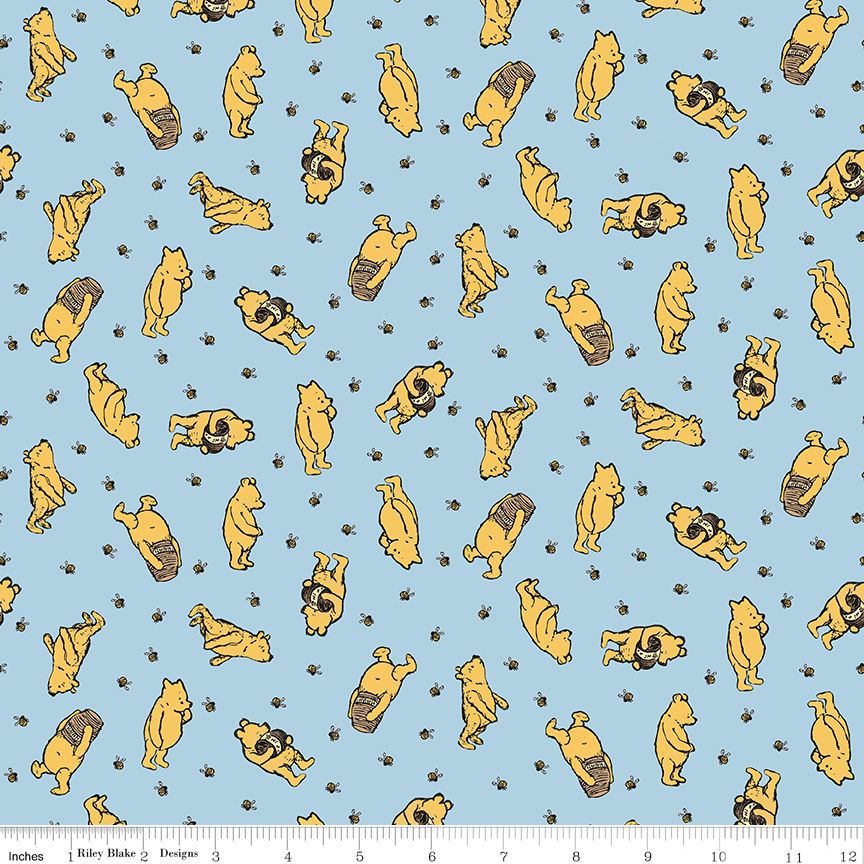 A fabric pattern featuring Winnie the Pooh on a light blue background, with a white ruler at the bottom showing measurements.