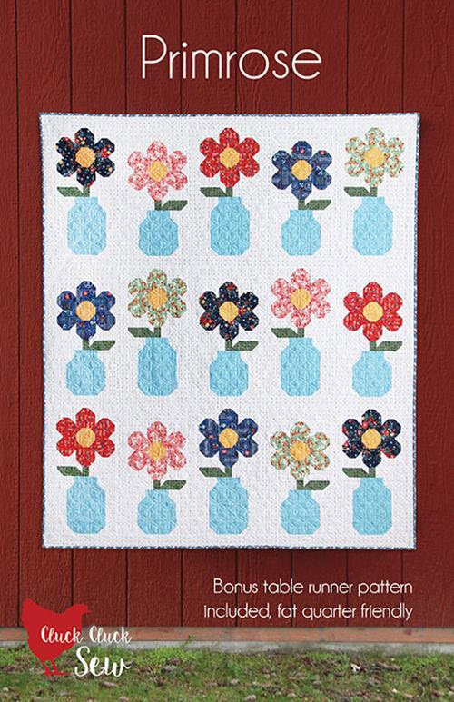 A quilt pattern cover titled "Primrose" showing a floral quilt with colorful flowers in blue vases on a white background, set against a red wood wall. Text at the bottom says "Bonus table runner pattern included, fat quarter friendly" and the Cluck Cluck Sew logo appears in the lower left.