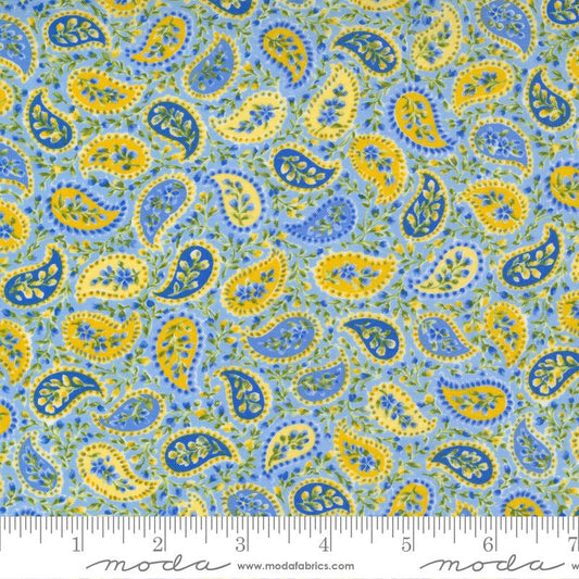 A close-up of a paisley fabric pattern with blue, yellow, and green motifs on a light blue background, with a ruler along the bottom showing scale and Modra branding.