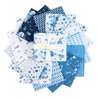 A collection of blue and white patterned fabric pieces arranged in a circular stack, with a central folded piece tied with a white ribbon. The fabrics feature various motifs including floral, geometric, and small illustrations.