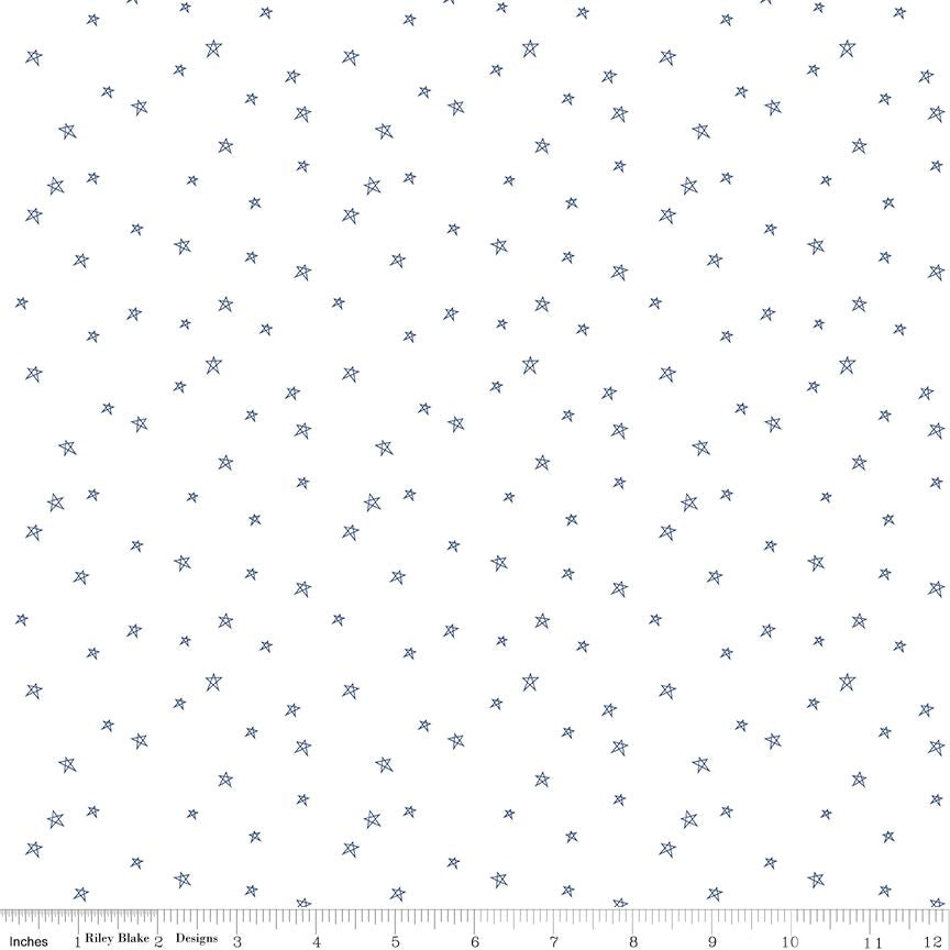 White fabric with a repeating pattern of small blue stars, shown with a ruler at the bottom indicating scale.