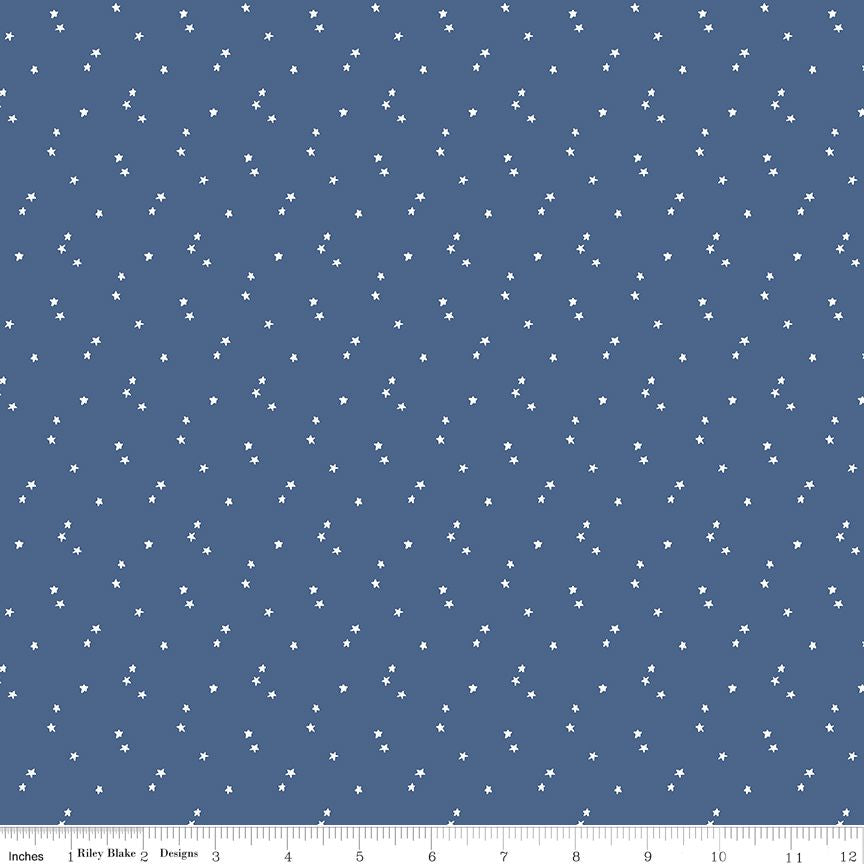 A fabric pattern swatch featuring small white stars scattered across a slate blue background, with a ruler scale at the bottom indicating 12 inches.