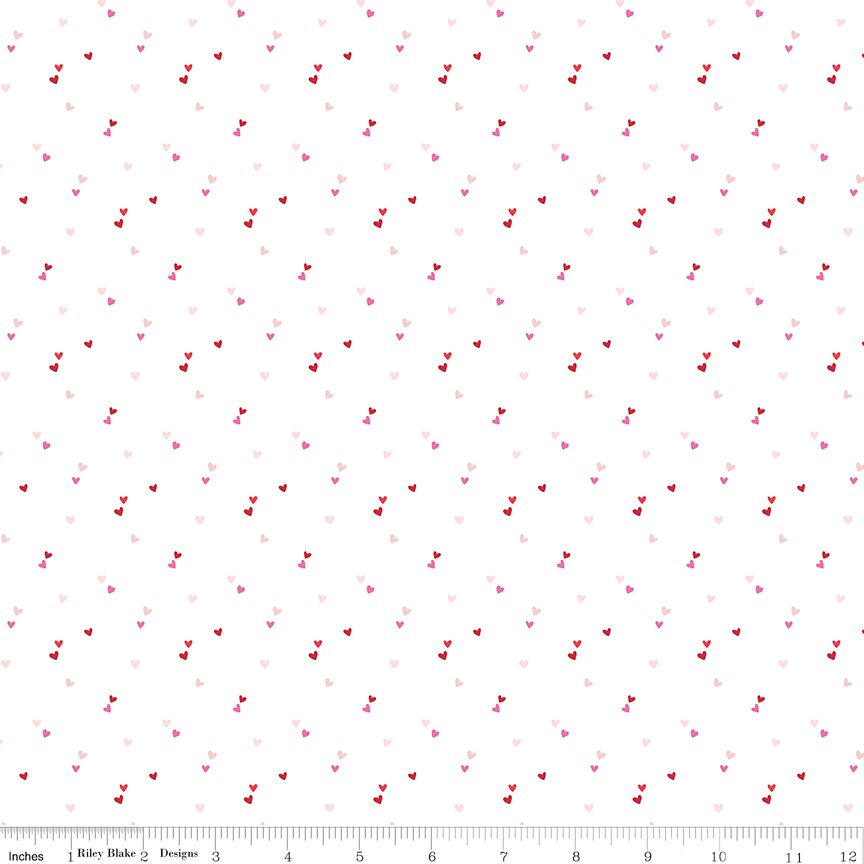 A repeating pattern of small hearts in shades of red, pink, and light pink on a white background, with a measuring ruler visible along the bottom edge.
