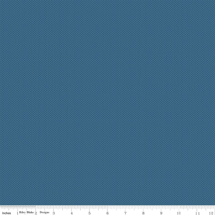 A close-up fabric pattern swatch showing a repeating diagonal grid or plaid-like design in denim blue, with a ruler strip along the bottom edge indicating scale.