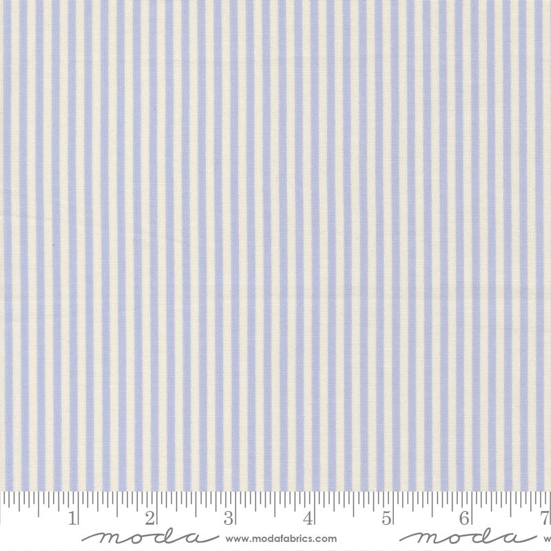 A close-up of a fabric pattern with vertical light blue and off-white stripes, shown with a ruler along the bottom edge for scale. The brand name 'moda' and website 'www.