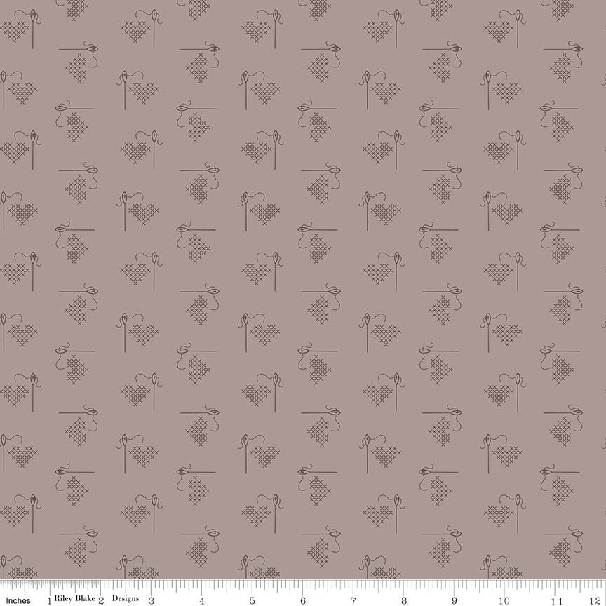 A repeating fabric pattern featuring dark grey embroidered-style hearts with thread and needle motifs on a pewter background, with a ruler along the bottom edge showing scale.