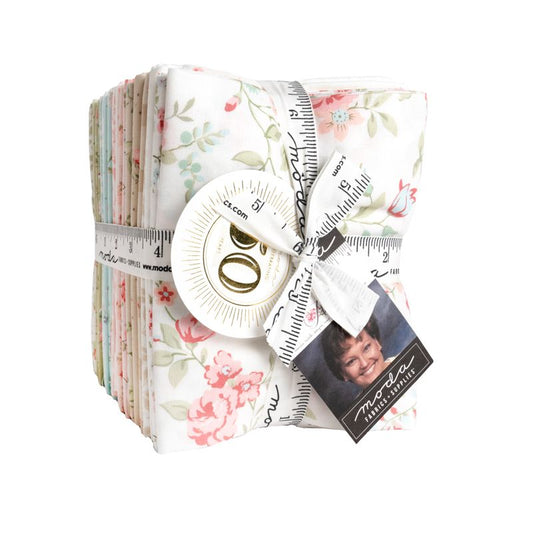 A bundle of floral quilting fabric pieces tied with a white measuring ribbon and bow, featuring a printed tag with a portrait and the brand name Martha Stewart.