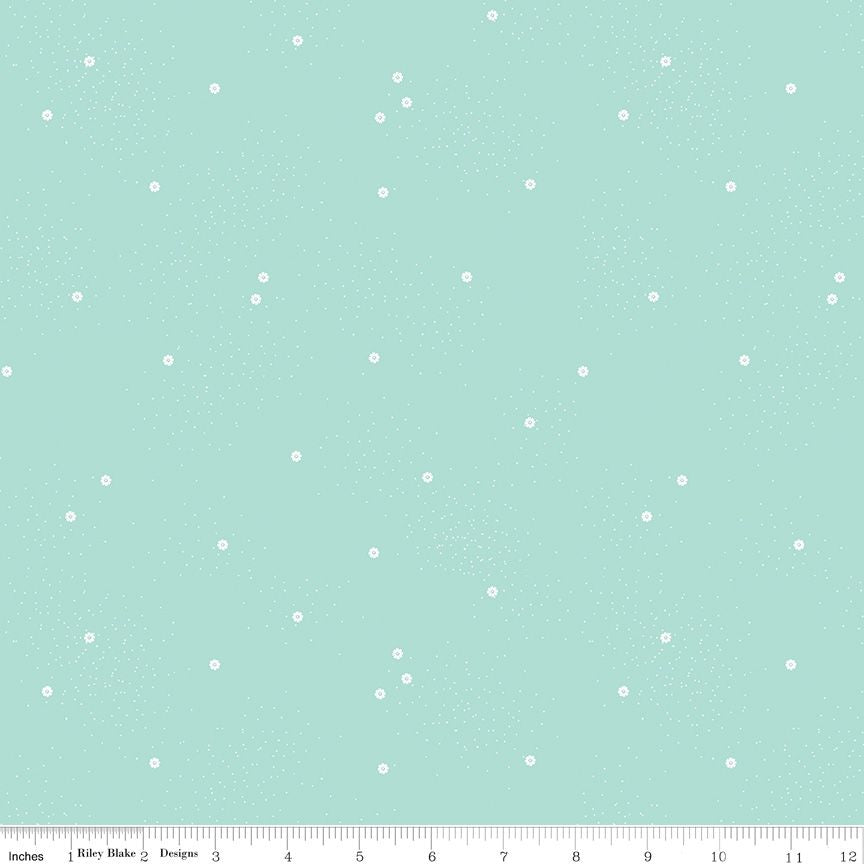 A pale blue fabric pattern featuring small scattered white daisies and tiny speckles, with a ruler along the bottom edge showing scale.
