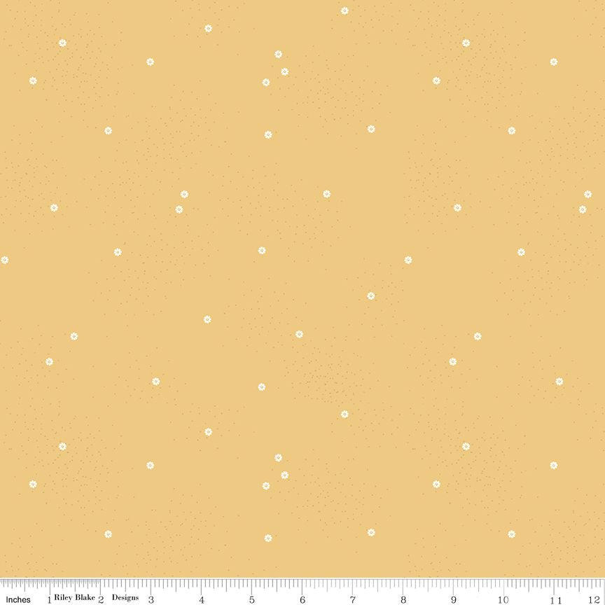 A fabric pattern swatch featuring a warm mustard yellow background with small, scattered white daisies. A white ruler at the bottom indicates the scale of the pattern.