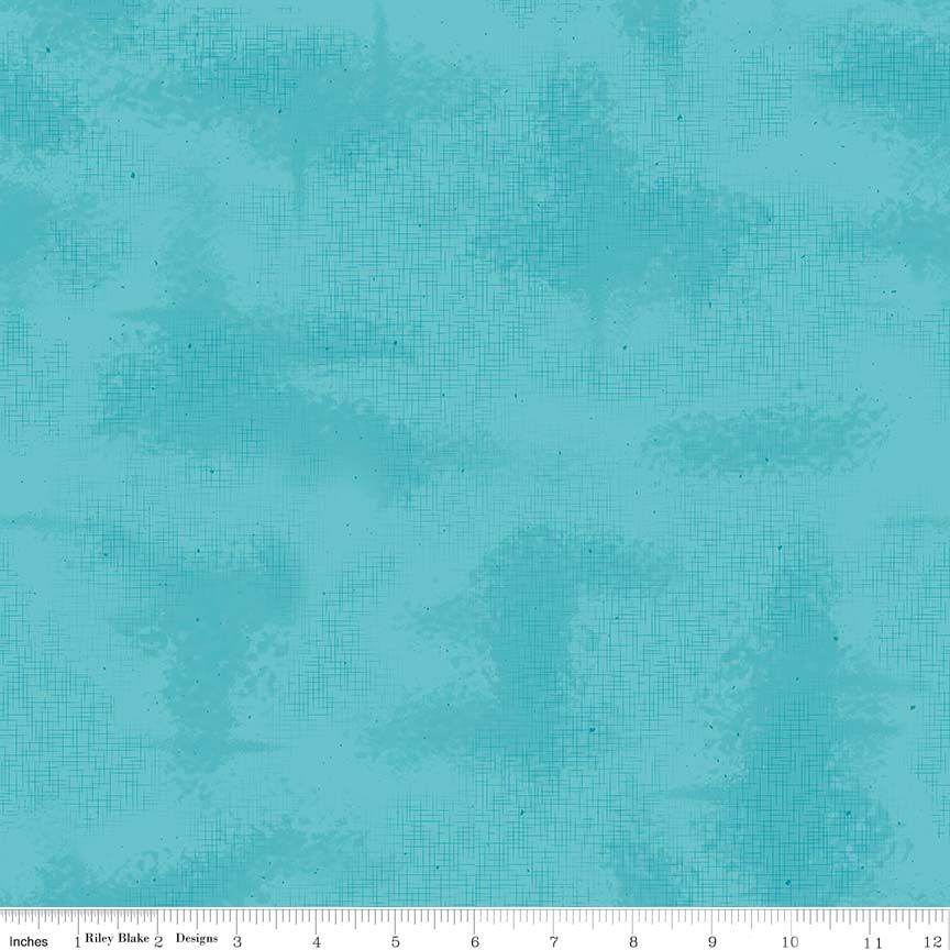 A close-up of a turquoise blue fabric texture with a subtle woven grid pattern and small dark specks, shown with a ruler at the bottom indicating scale.