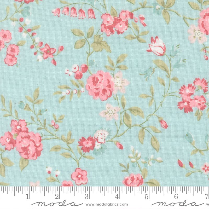 Floral fabric pattern with pink and red flowers, green leaves, and small white blossoms on a light aqua background, shown with a measuring ruler along the bottom edge. The brand name Moda is visible at the bottom.