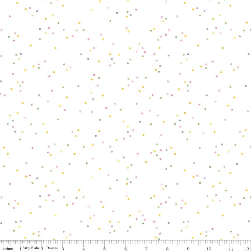 White fabric with a scattered confetti pattern of tiny pastel flowers in pink, yellow, green, and blue, with a 12-inch ruler scale along the bottom edge.