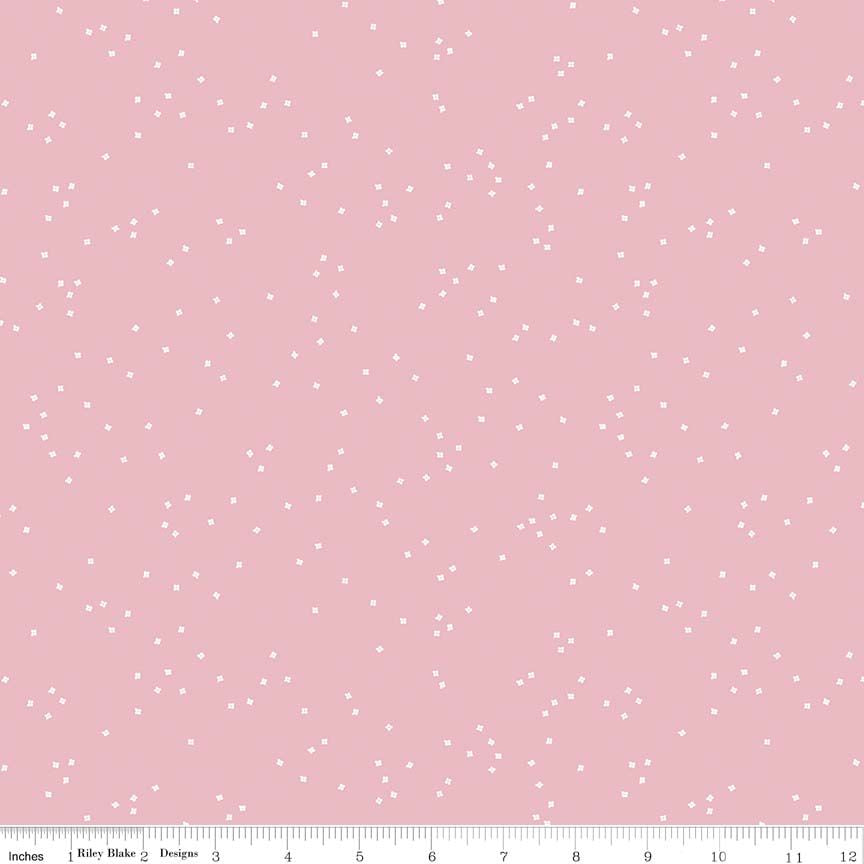 Pink fabric with a scattered tiny white flower pattern, shown with a ruler at the bottom indicating scale.