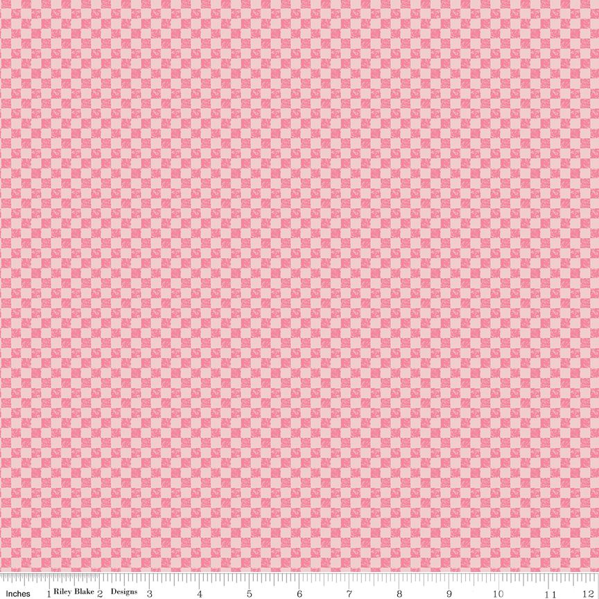 Light pink and dark pink checkerboard patterned fabric with a measuring ruler along the bottom edge showing scale.