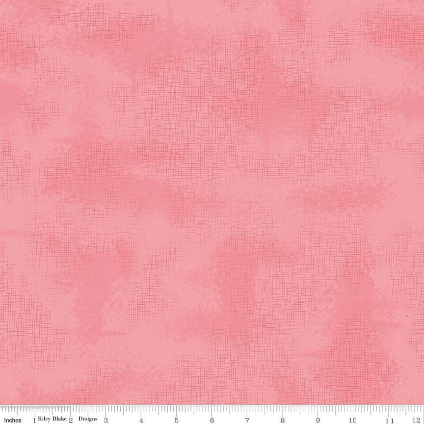 A close-up of a pink textured fabric with a subtle crosshatch or linen-like pattern, shown with a ruler along the bottom edge for scale.