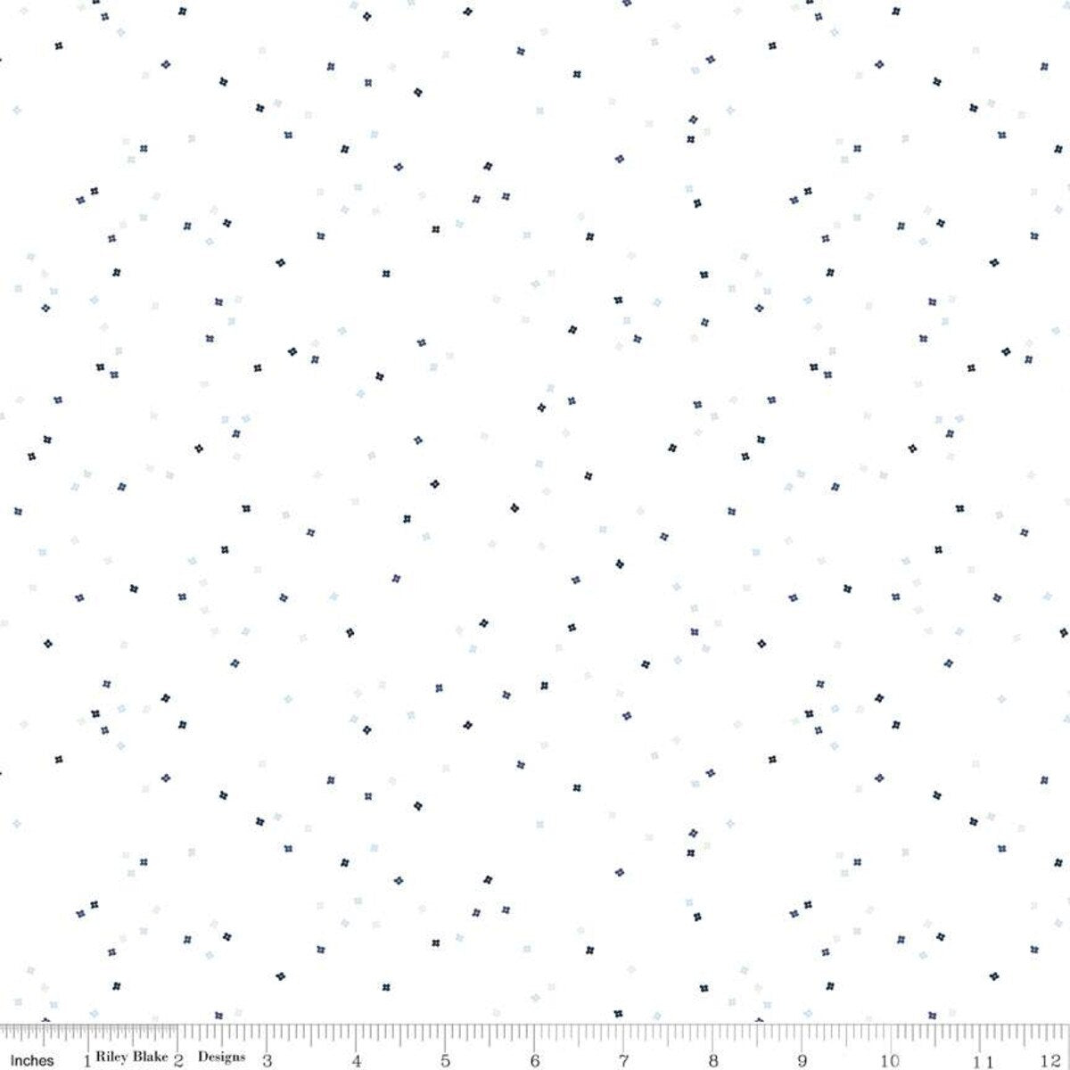 White background with tiny flowers in varying shades of blue with a ruler at the bottom for scale.