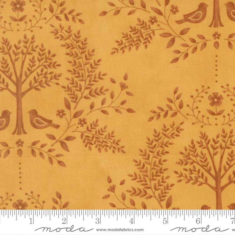 Fabric with brown tree and bird pattern on a gold background, featuring a ruler at the bottom.