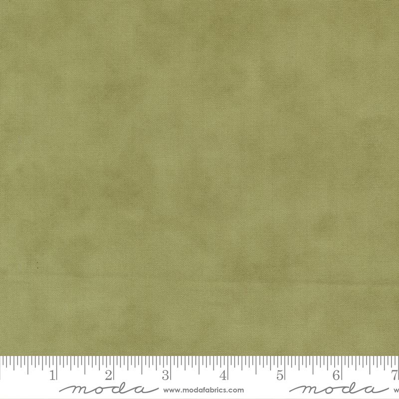 A close-up of olive green fabric texture with a white ruler along the bottom edge showing measurement markings and Modas Fabrics branding.