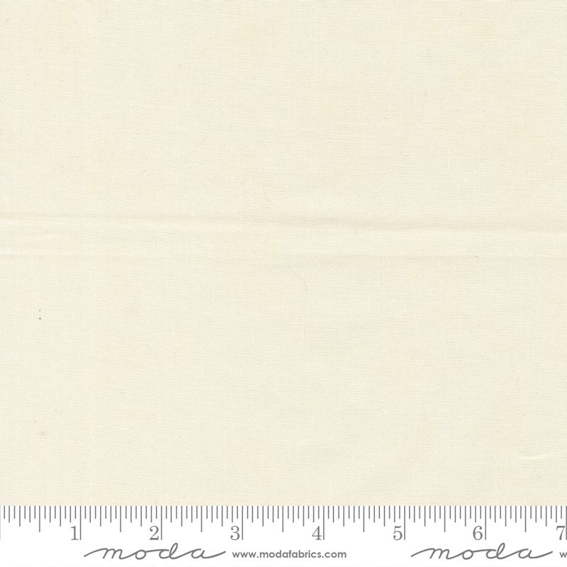 A close-up of a light cream fabric texture with a ruler along the bottom edge showing measurement markings and a Modra watermark.