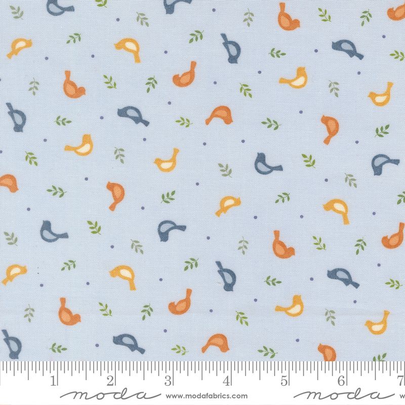 Light blue fabric with a repeating pattern of small orange, yellow, and navy birds, green leaves, and blue dots, with a Modas Fabrics ruler along the bottom edge.