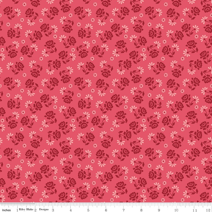 A repeating floral pattern on a pink background, featuring dark red roses and small pale pink flowers. A white ruler along the bottom edge shows the scale of the pattern.
