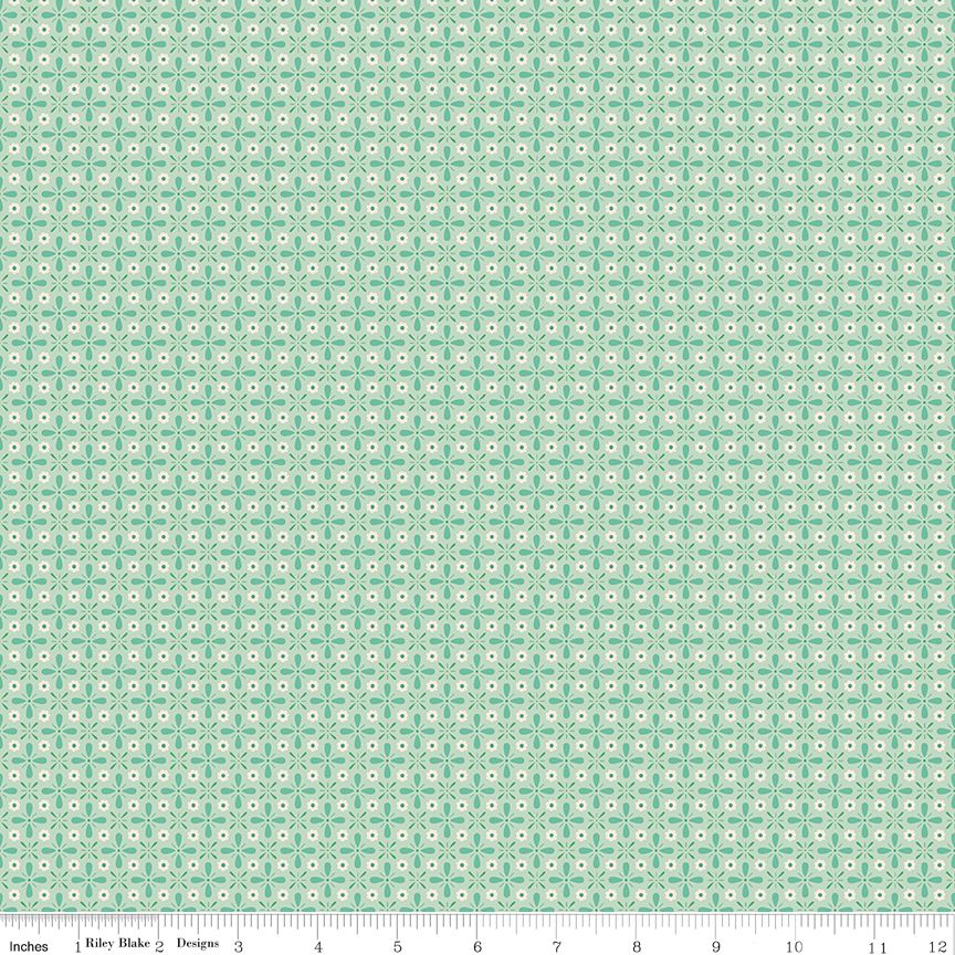 A repeating fabric pattern featuring a mint green and white geometric medallion design, with a white ruler scale at the bottom indicating inches and showing the brand 'Riley Blake Designs'.