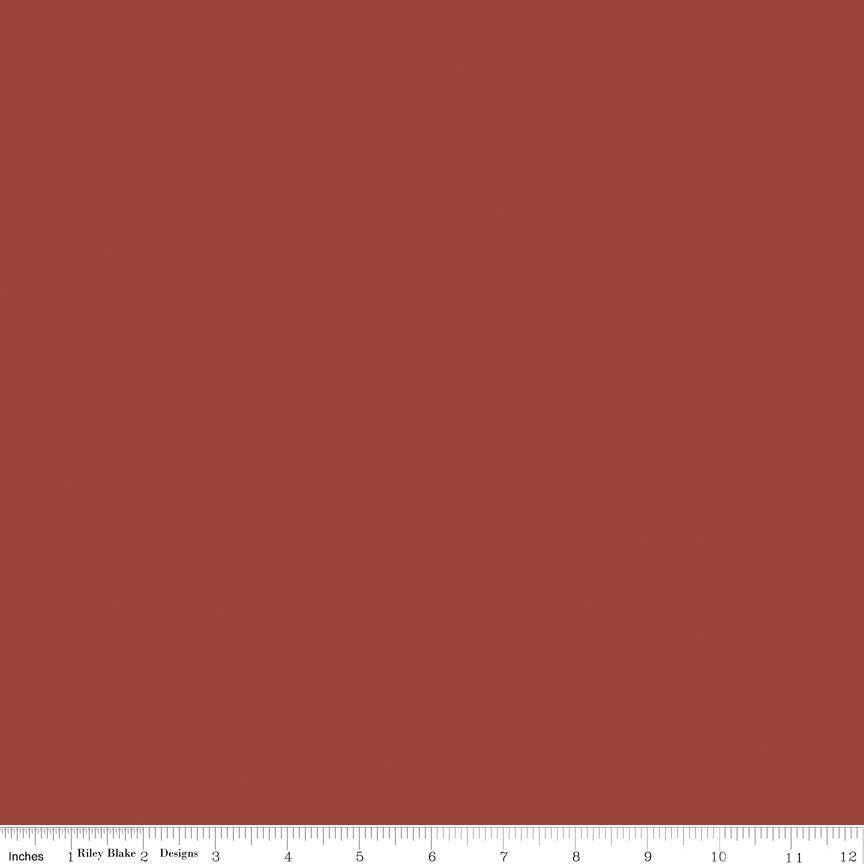 A solid rust-brown fabric swatch with a white measurement ruler along the bottom edge showing inches and centimeters.