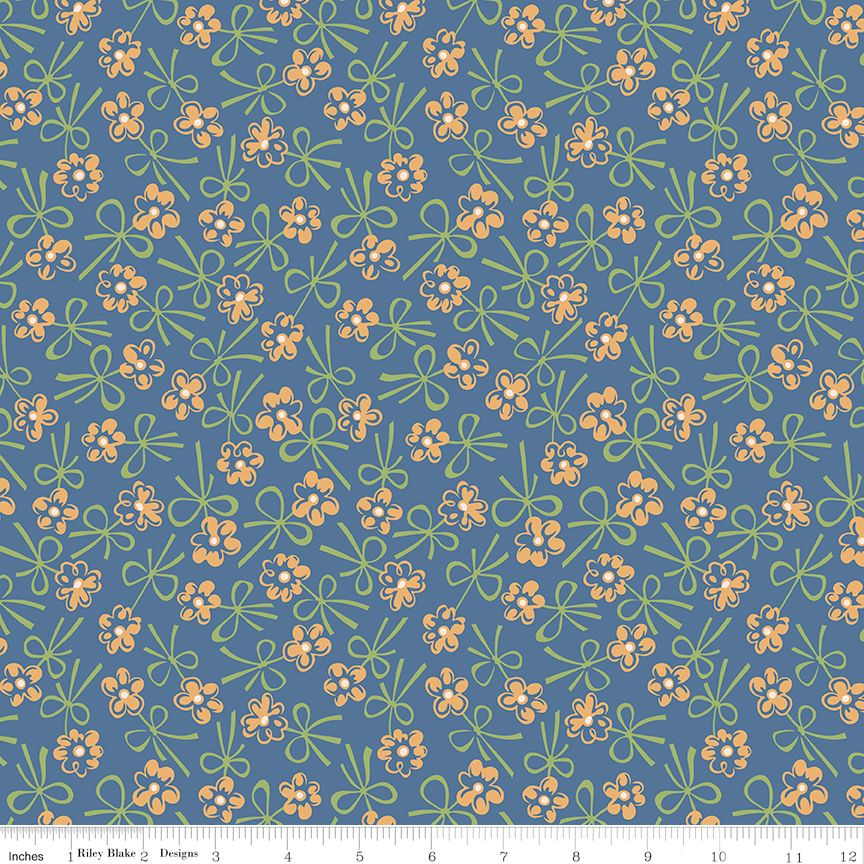 A repeating fabric pattern featuring yellow flowers with white centers and light green leaves on a muted blue background, shown with a ruler along the bottom edge indicating scale.