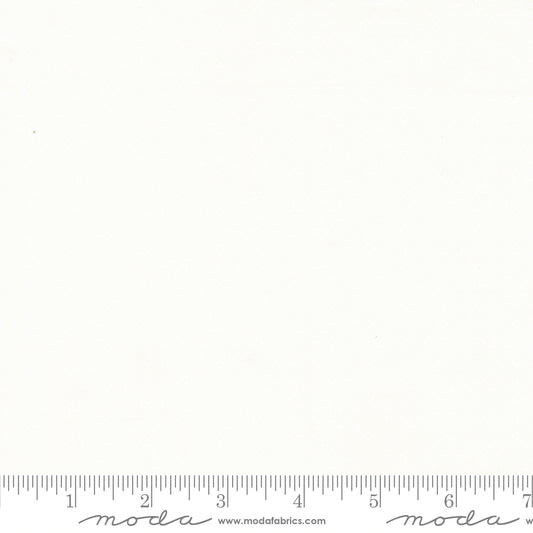 A white-on-white eyelet pattern fabric with a gray ruler printed along the bottom edge and the Moda Fabrics logo and website printed below the ruler.
