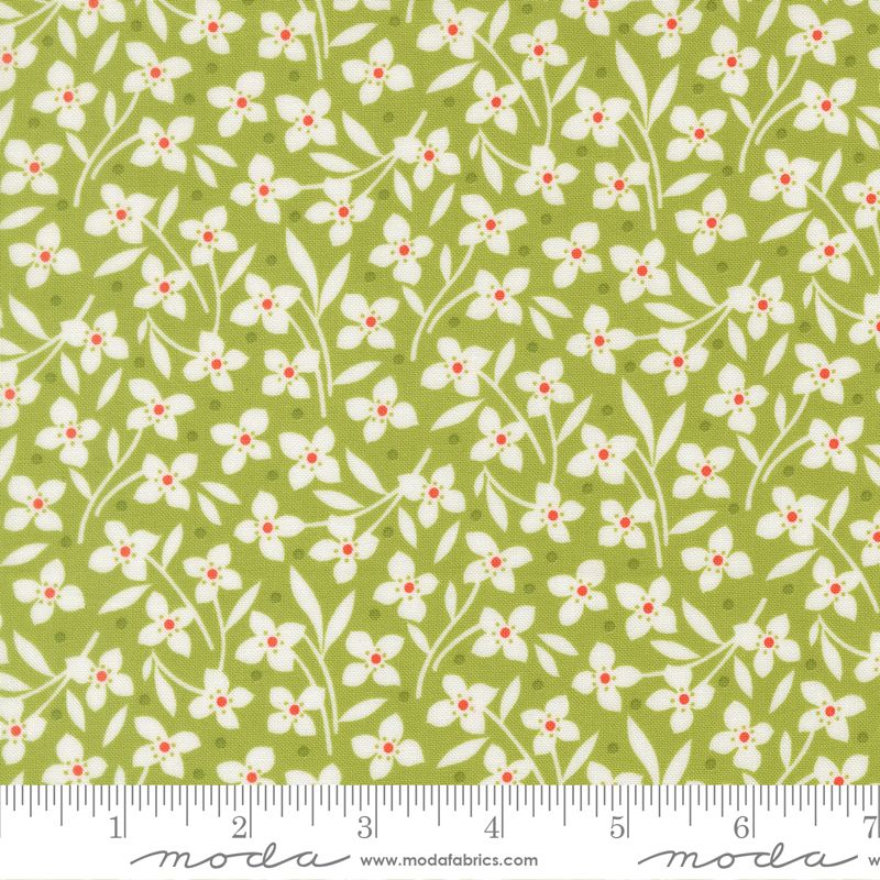 A repeating fabric pattern featuring small white flowers with orange centers and green leaves on an olive green background, shown with a measuring ruler along the bottom edge.