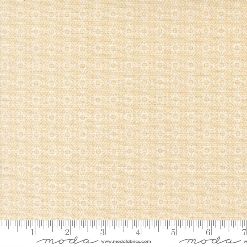 A close-up of a fabric pattern swatch with a repeating geometric diamond design in pale yellow and off-white, with a measuring ruler along the bottom edge showing Moda Fabrics branding.