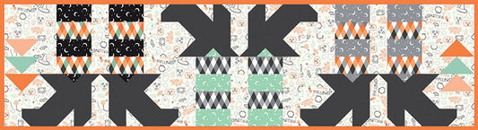 Quilted table runner of witches feet with Halloween colored socks with patterns in black, orange, gray, and green on a white background
