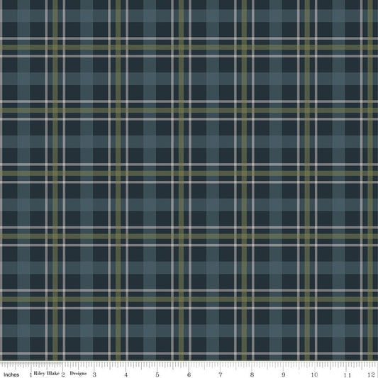 A close-up of a plaid fabric pattern in slate blue, navy, olive green, and white, with a ruler along the bottom edge showing measurement markings.