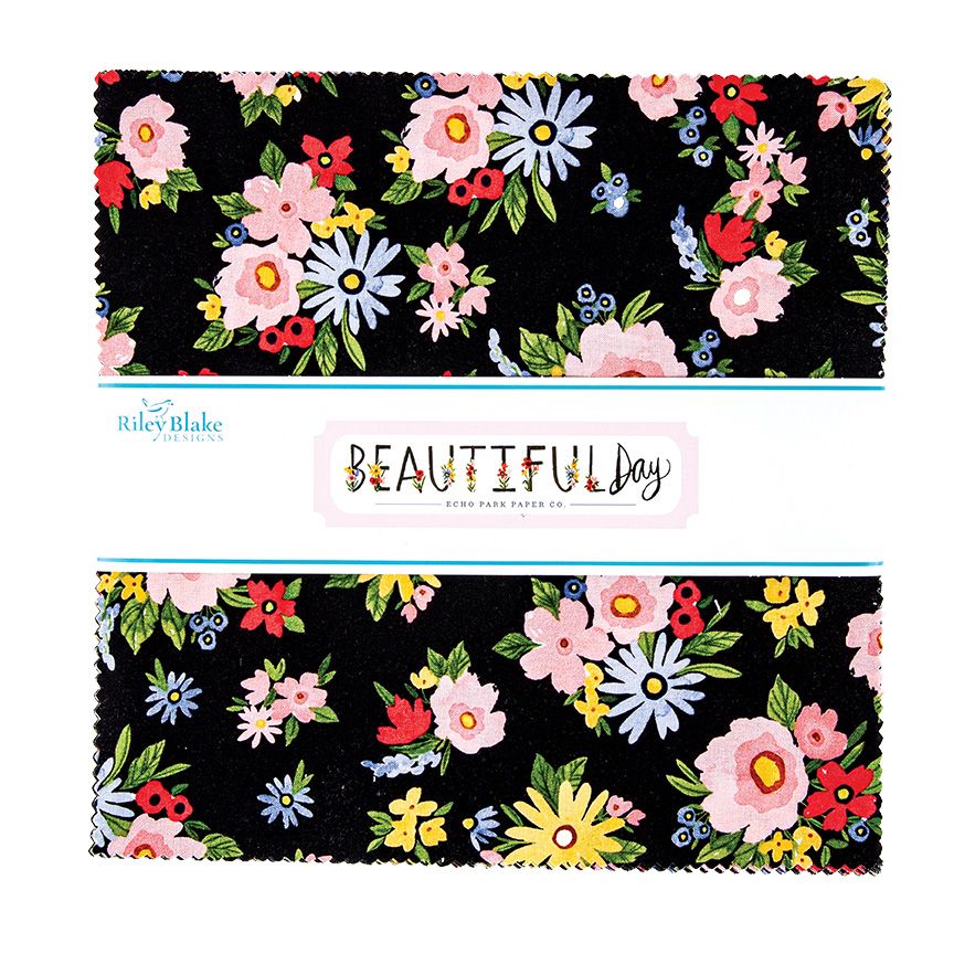 Fabric layer cake with a colorful floral print on a black background, with a white paper band labeled Riley Blake Fabrics and Beautiful Day.