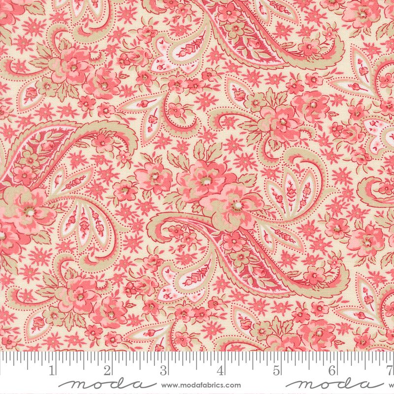 A close-up of a fabric pattern featuring pink and coral floral paisley motifs on a warm cream background, with a ruler along the bottom edge showing scale. The brand name 'moda' is visible in script at the bottom.