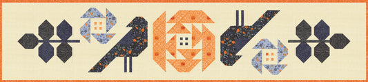 A quilted table runner featuring stylized birds, flowers, and geometric shapes in navy, orange, blue, and cream on a light beige background.