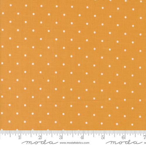 Fabric with white polka dots on a gold background, featuring Moda label.