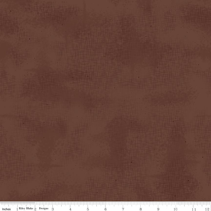 A close-up of a brown textured fabric with a subtle crosshatch pattern, featuring a white ruler at the bottom edge for scale.