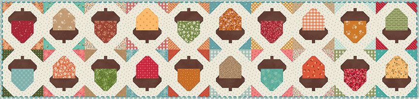 A repeating quilted table runner of acorns in many colors, including red, orange, yellow, green, brown, and blue, arranged in rows on a cream and patterned background.