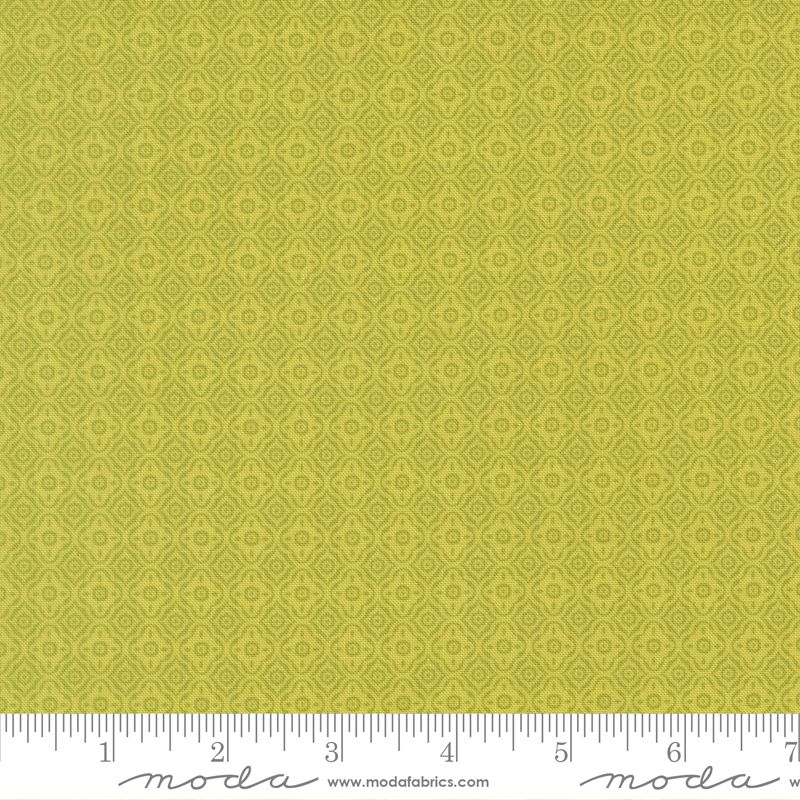 Green patterned fabric with a ruler at the bottom for scale, featuring the brand 'Moda'.