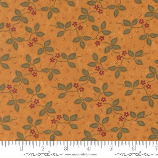 A close-up of a fabric pattern featuring green leaves and small red flowers on a warm orange-brown background, with a white ruler along the bottom edge showing measurement markings and a Modas fabric watermark.