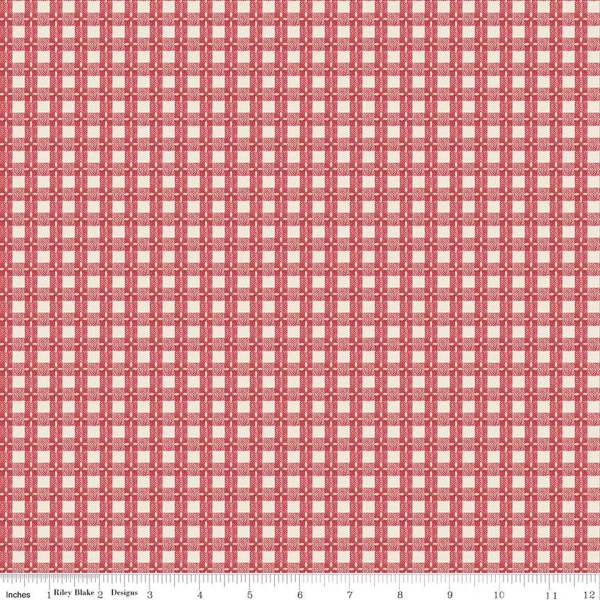 A close-up of a repeating fabric pattern in coral red and cream, with a ruler along the bottom edge showing scale.