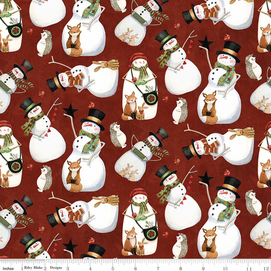 A repeating holiday pattern on a dark red background featuring white snowmen with black top hats, green scarves, red hats, brown foxes, small owls, and stars. A ruler edge is visible along the bottom with the text 'Riley Blake Designs'.