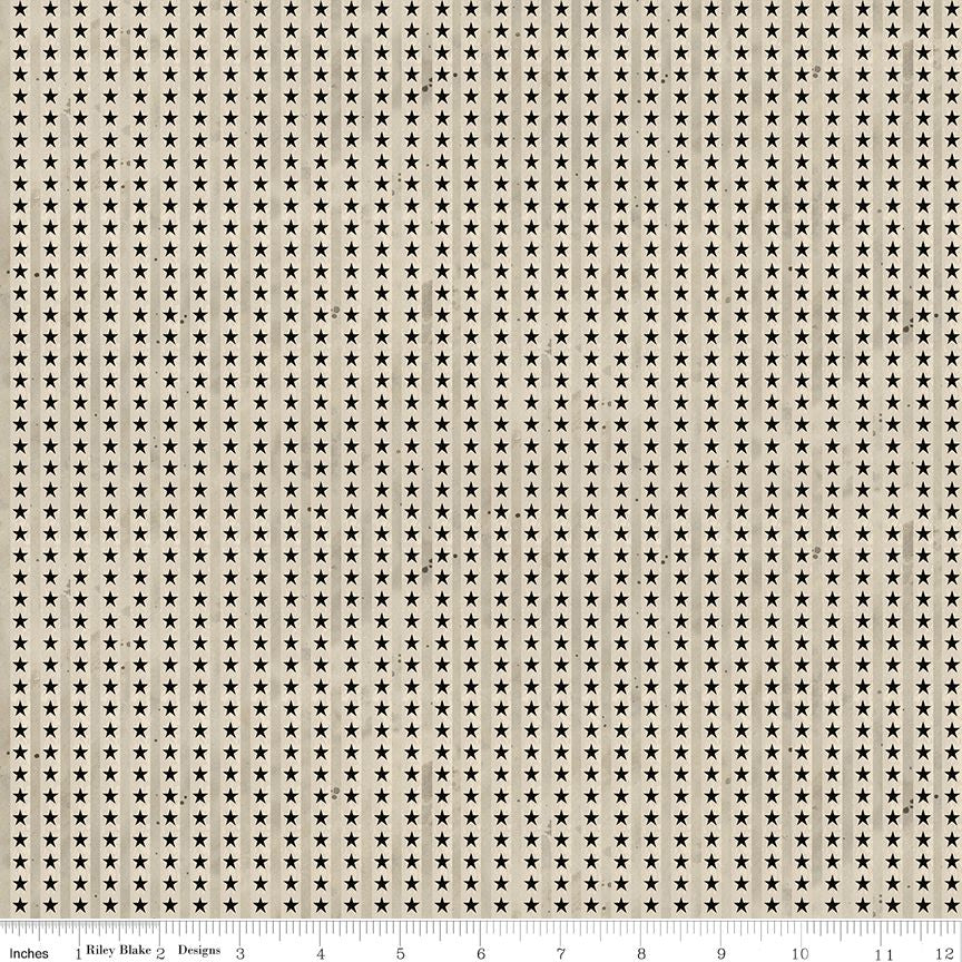 A close-up of a fabric pattern featuring a repeating grid of small black six-pointed stars on a warm beige background, with a ruler scale at the bottom indicating the pattern repeats.